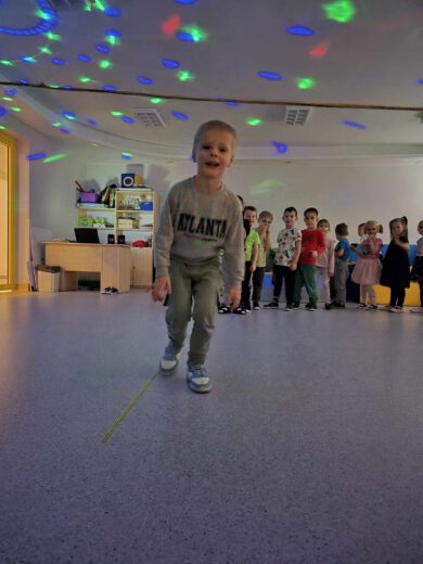 chłopiec idzie tanecznym krokiem, za nim grupa dzieci